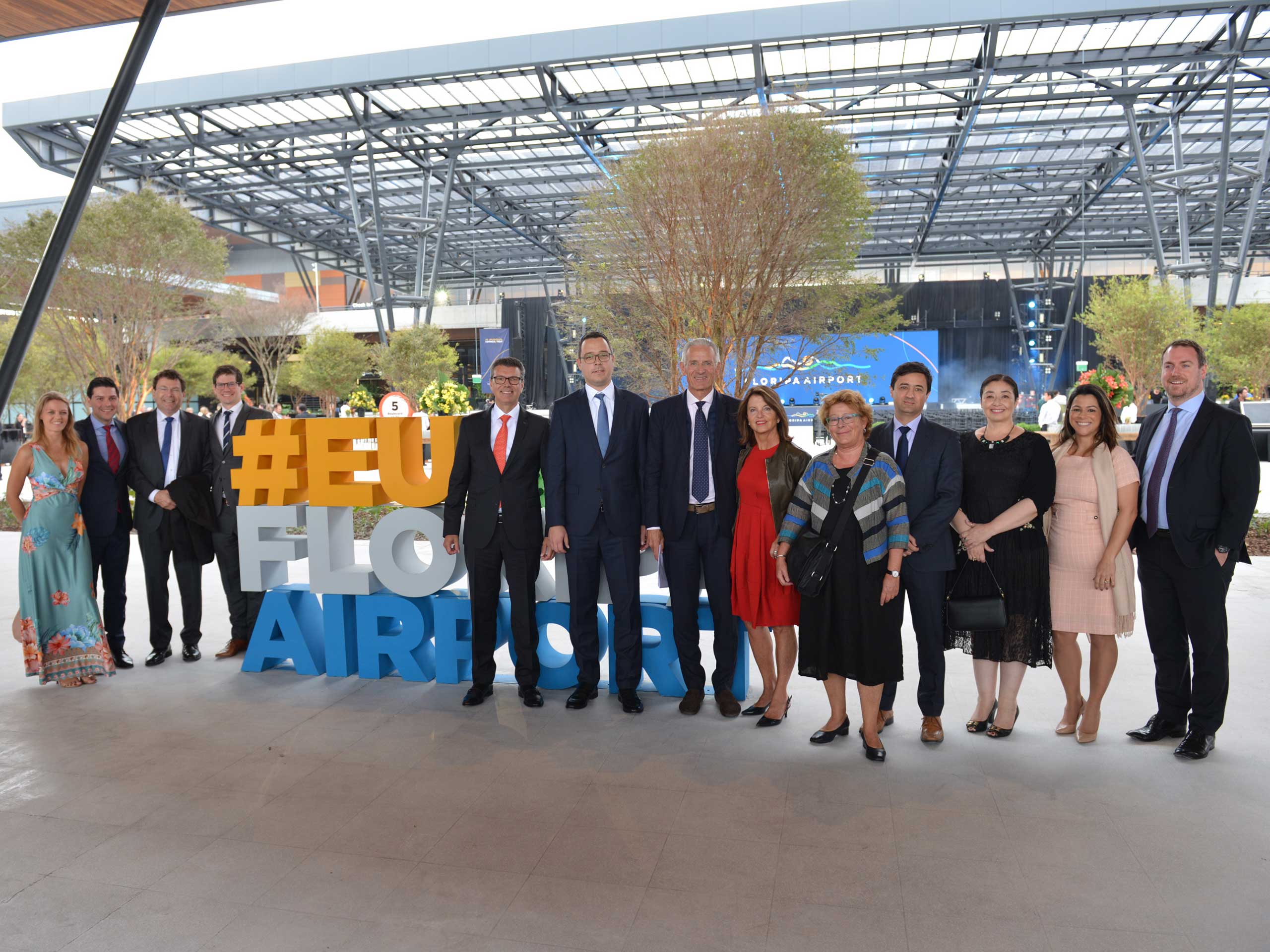 The graphic shows a ceremonial opening in Florianópolis, Brazil, in 2019. Several airport specialists stand next to each other under a transparent glass roof.